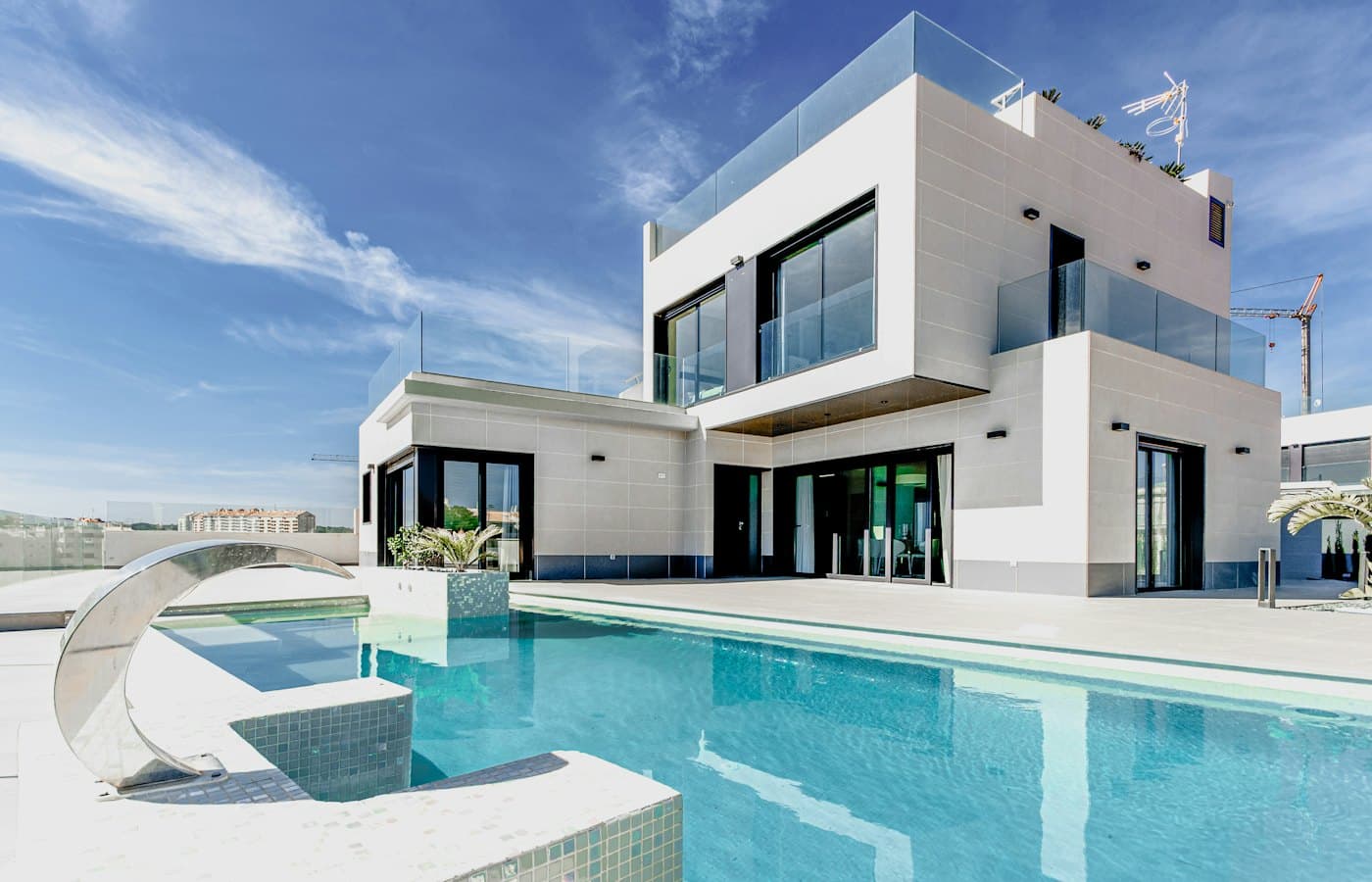 Modern white two-storey home with large windows under a clear blue sky