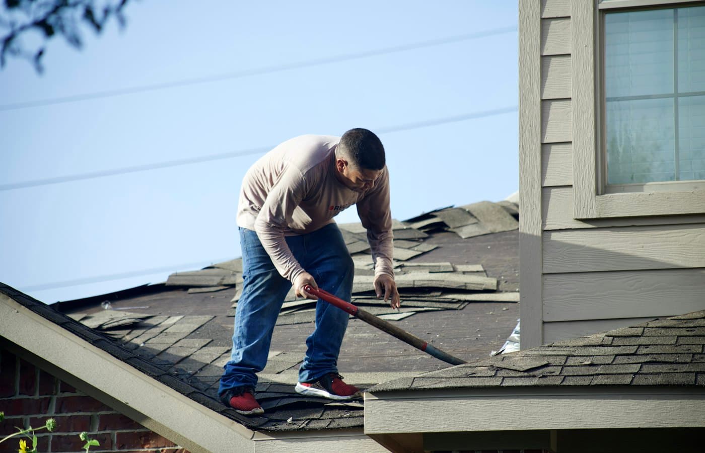 Roofer removing old shingles from a residential roof